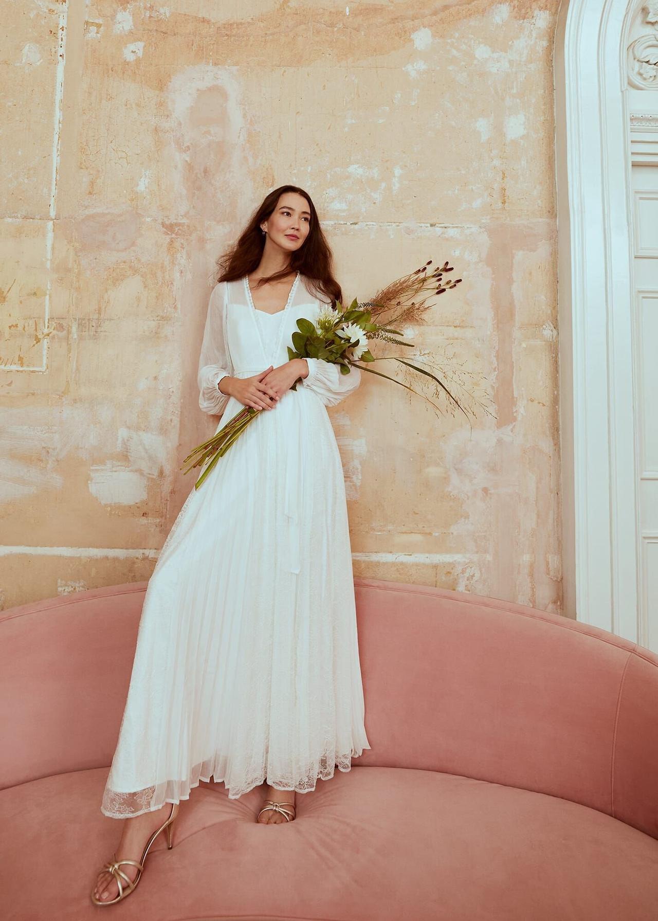 Model care poarta o rochie de mireasa simpla plisata alba